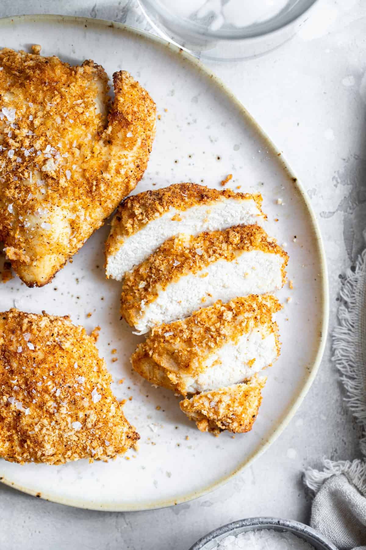Crispy Breaded Air Fryer Chicken Breast - SO crispy you won't believe how healthy and easy it is to make! Great for busy weeknights and for picky eaters! There is a gluten free option included! | #Foodfaithfitness | #Glutenfree #Healthy #Kidfriendly #Airfryer #Nutfree overhead image of sliced Air Fryer Breaded Chicken Breast on a plate