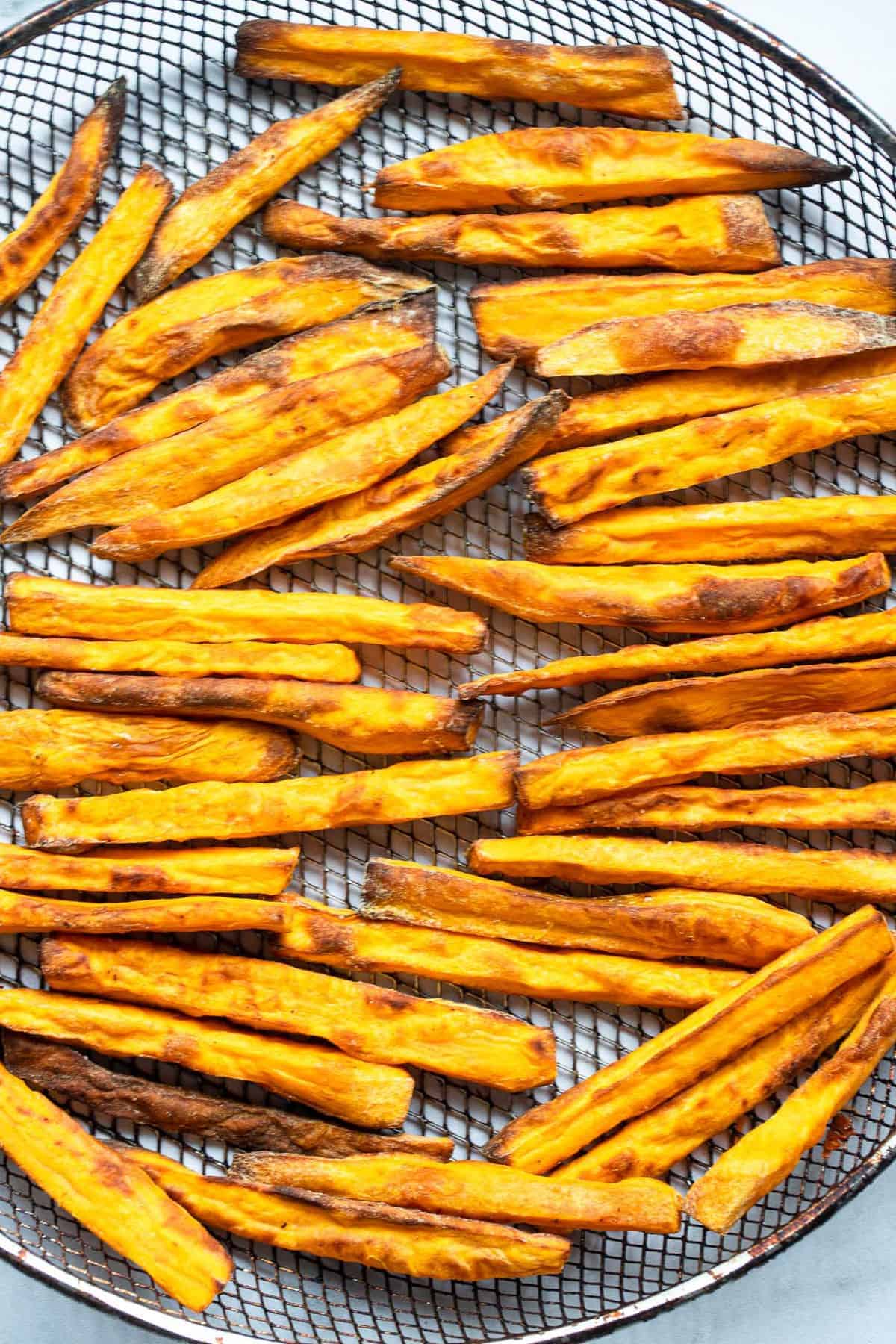 Air Fryer Sweet Potato Fries - These Air Fryer Sweet Potato Fries are only 3 simple ingredients and are so crispy! Naturally gluten free, vegan, paleo & whole30 too! | #Foodfaithfitness | #Glutenfree #paleo #vegan #whole30 #healthy air fried sweet potato fries on a mesh basket