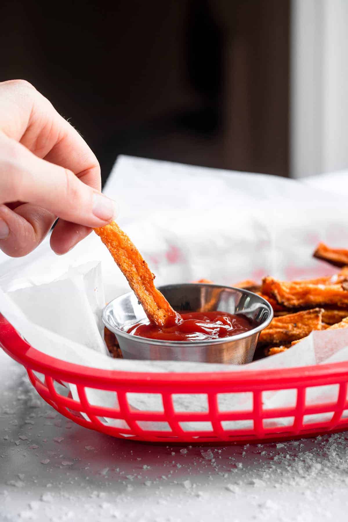 CRISPY Baked Sweet Potato Fries - These Crispy Baked Sweet Potato Fries are SO crispy, but healthy! Learn the secret ingredient that will have you never missing the deep fried version again! | #Foodfaithfitness | #glutenfree #paleo #vegan #whole30 #healthy baked sweet potato fries in a serving basket with ketchup
