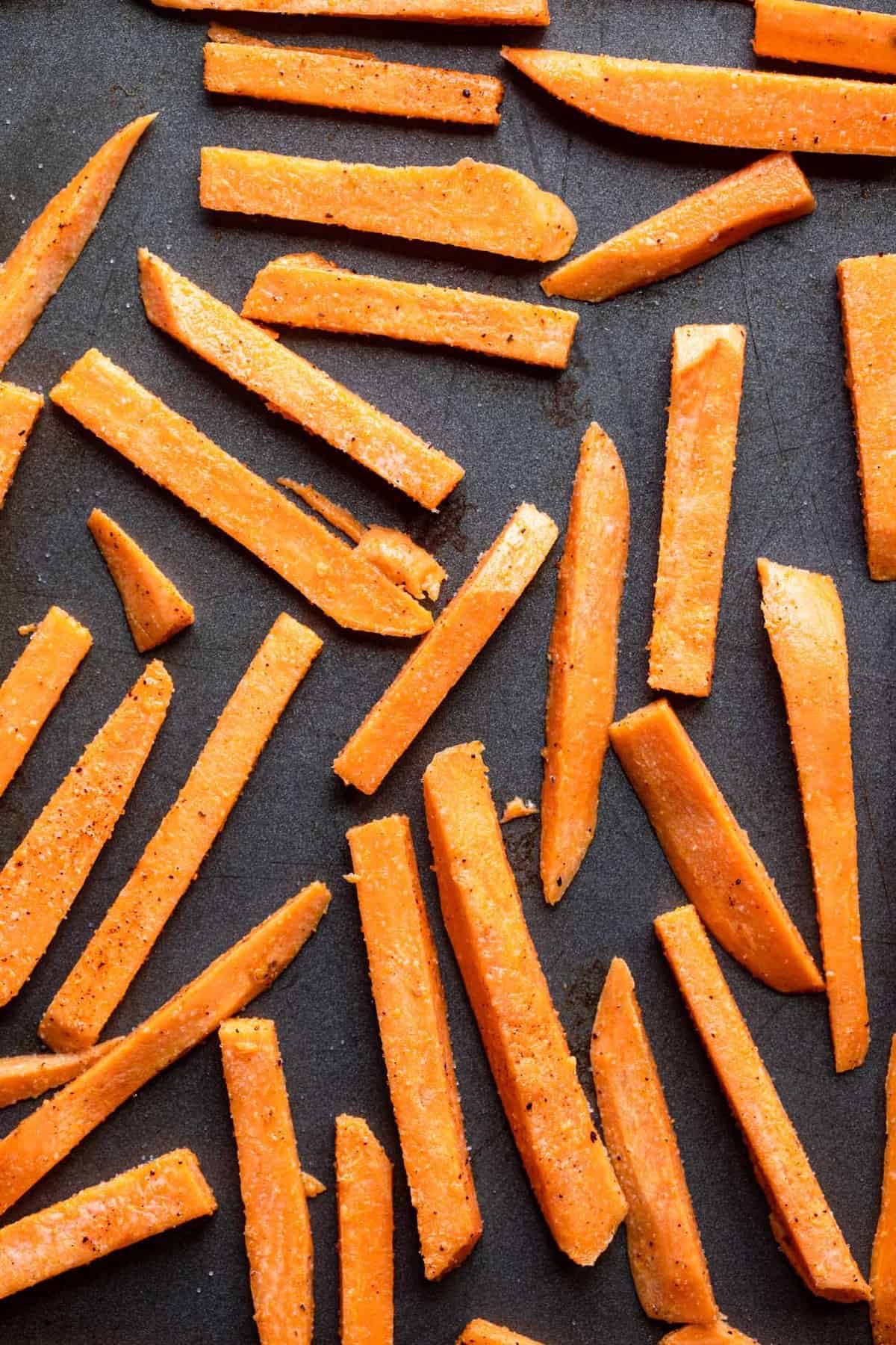 CRISPY Baked Sweet Potato Fries - These Crispy Baked Sweet Potato Fries are SO crispy, but healthy! Learn the secret ingredient that will have you never missing the deep fried version again! | #Foodfaithfitness | #glutenfree #paleo #vegan #whole30 #healthy sweet potatos sliced on a baking sheet ready to be cooked for baked sweet potato fries
