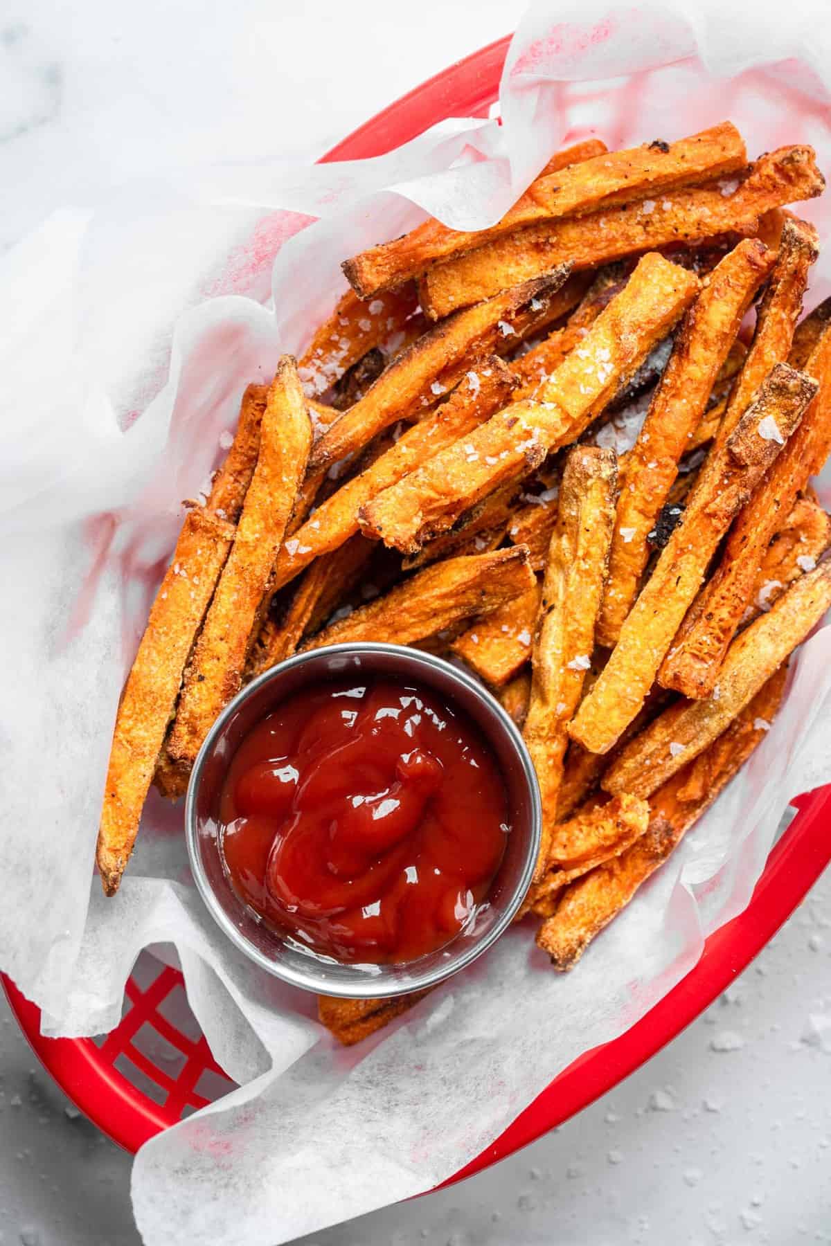 CRISPY Baked Sweet Potato Fries - These Crispy Baked Sweet Potato Fries are SO crispy, but healthy! Learn the secret ingredient that will have you never missing the deep fried version again! | #Foodfaithfitness | #glutenfree #paleo #vegan #whole30 #healthy close up of baked sweet potato fries with seasoning and ketchup on the side