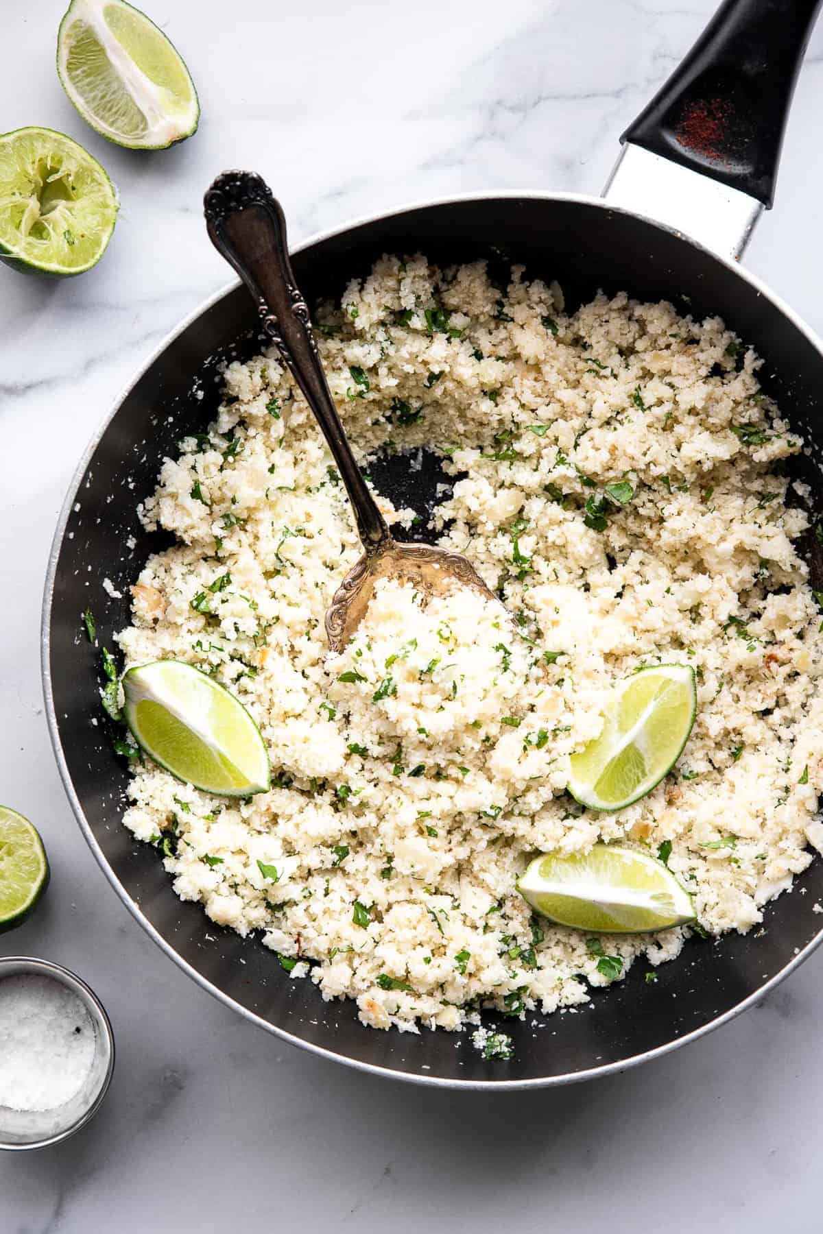 Cilantro Lime Cauliflower Rice - This Cilantro Lime Cauliflower Rice is an easy, 5 ingredient recipe that is a healthy, gluten free and low carb side dish for the whole family! | #Foodfaithfitness | #Keto #Lowcarb #glutenfree #paleo #whole30 cilantro lime cauliflower rice in a skillet on a table