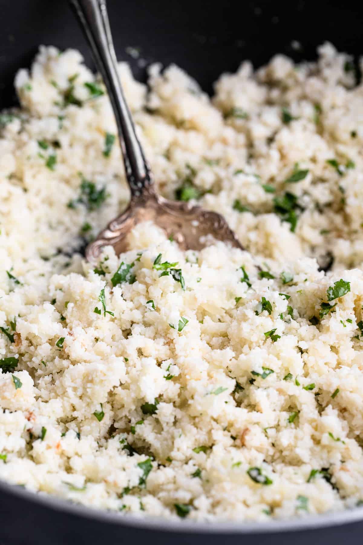 Cilantro Lime Cauliflower Rice - This Cilantro Lime Cauliflower Rice is an easy, 5 ingredient recipe that is a healthy, gluten free and low carb side dish for the whole family! | #Foodfaithfitness | #Keto #Lowcarb #glutenfree #paleo #whole30 cilantro lime cauliflower rice in a skillet with a serving spoon
