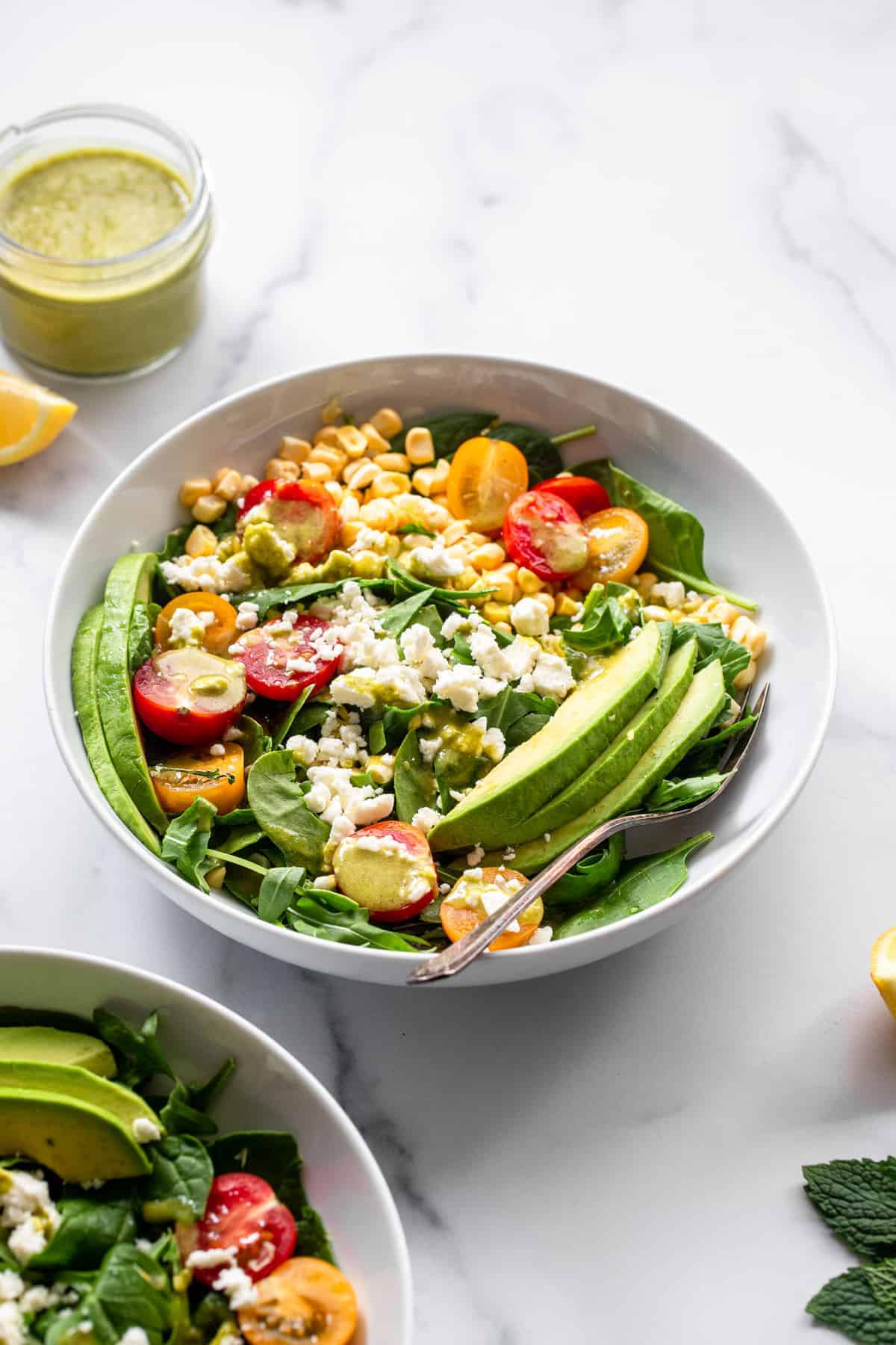 Fresh Corn and Feta Salad - This Fresh Corn Feta Salad is a gluten free, healthy no-cook Summer meal with the BEST mint vinaigrette! Even picky husbands love this salad! | #Foodfaithfitness | #Glutenfree #healthy #Corn #Salad corn feta salad in a bowl with avocado toppings