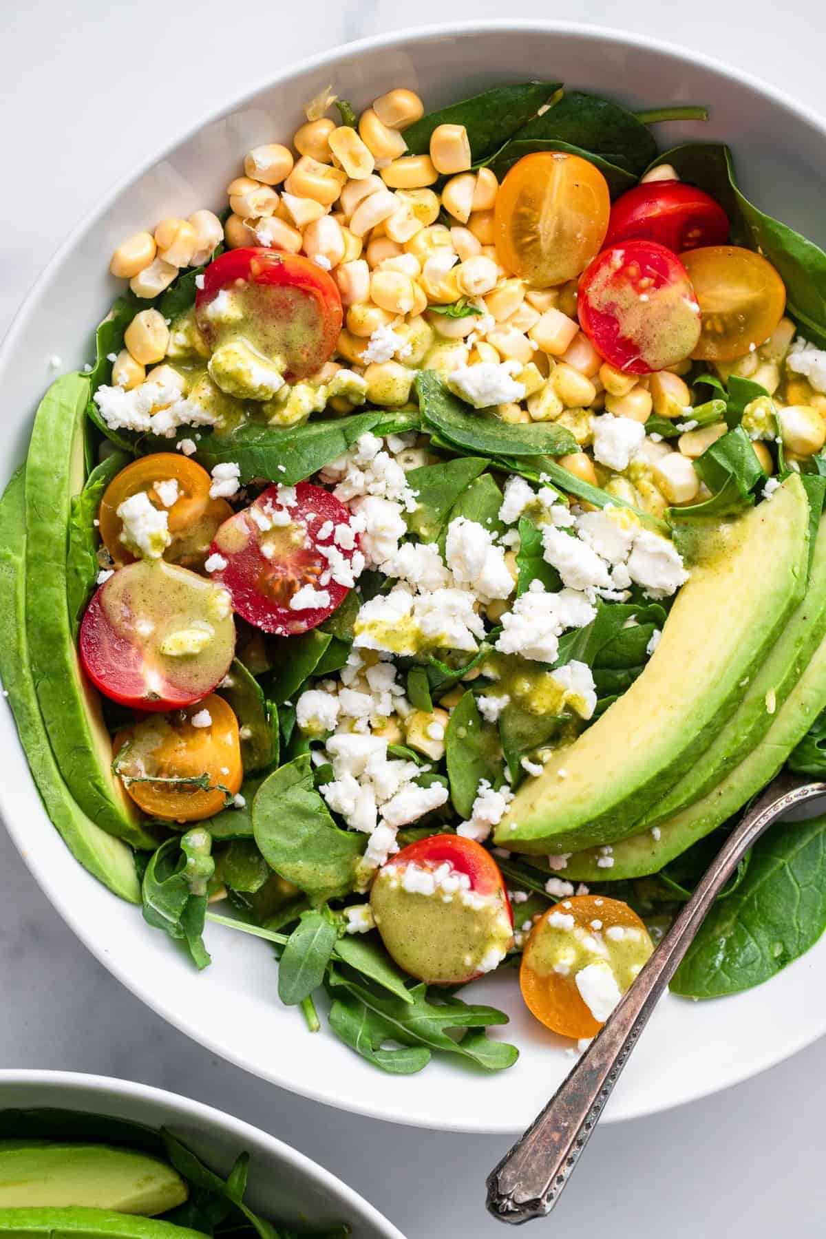 Fresh Corn and Feta Salad - This Fresh Corn Feta Salad is a gluten free, healthy no-cook Summer meal with the BEST mint vinaigrette! Even picky husbands love this salad! | #Foodfaithfitness | #Glutenfree #healthy #Corn #Salad close up view of corn feta salad in a bowl with a spoon