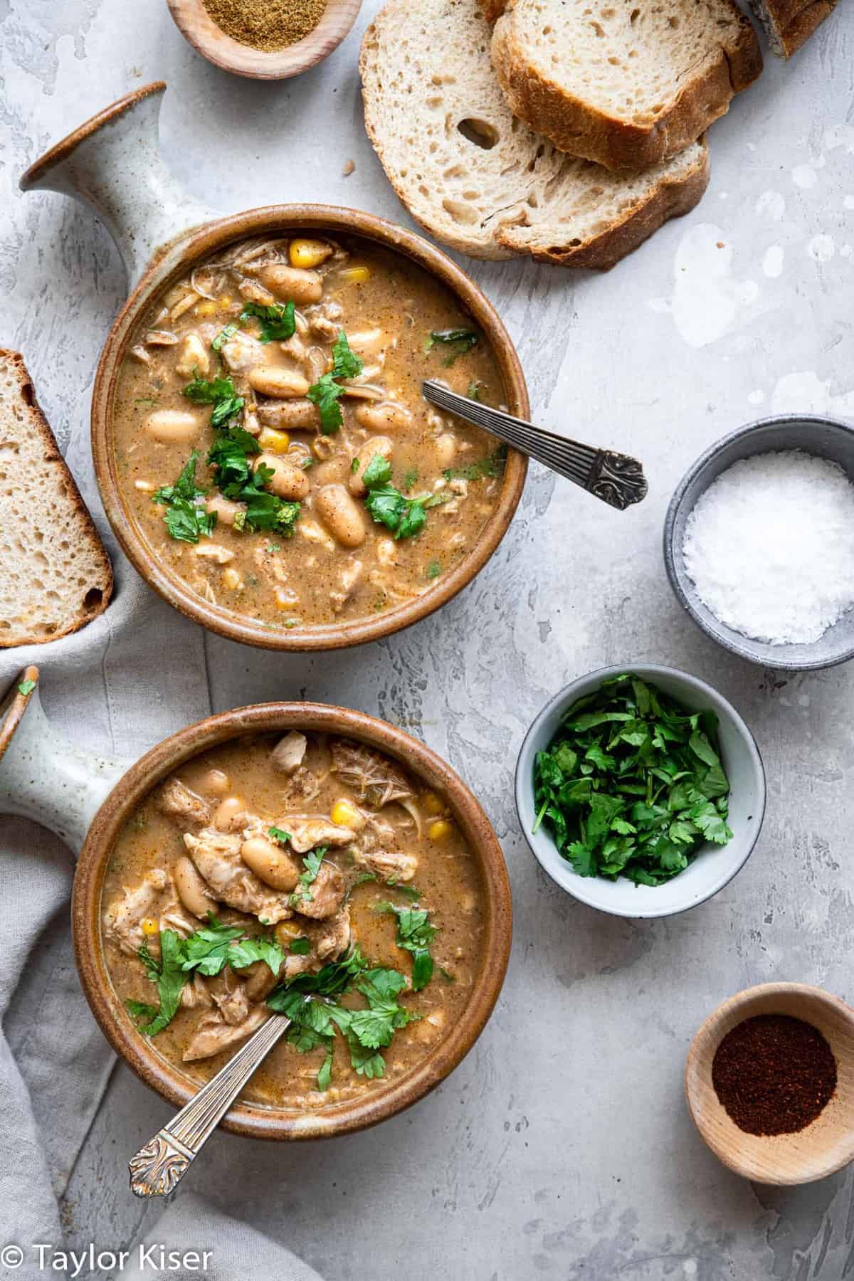 Healthy White Chicken Chili - This chicken chili is cooked in the crockpot for an easy, weeknight dinner that is naturally gluten and dairy free, simple and so tasty! Great for the whole family! | #Glutenfree #dairyfree #healthy #crockpot #soup two bowls of Crockpot White Chicken Chili with cilantro and salt