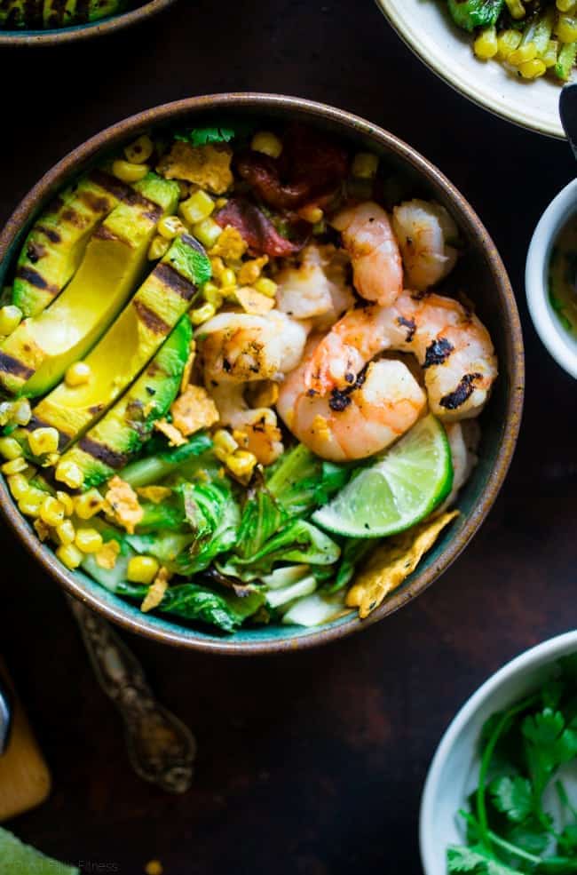Honey Lime Grilled Avocado Shrimp Nacho Bowls - These smoky-sweet bowls have glazed honey lime grilled avocado, spicy shrimp. tomato and corn! Top them with gluten free nacho chips for a healthy, summer meal that's packed with flavor! | Foodfaithfitness.com | @FoodFaithFit