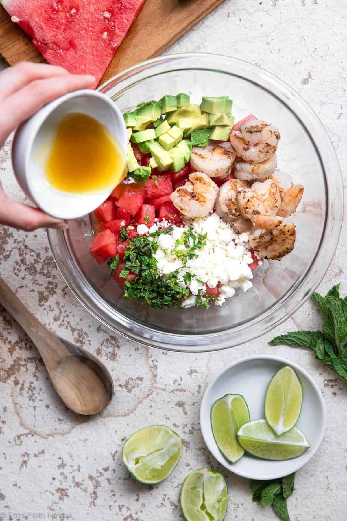 Shrimp Avocado Salad with Watermelon - An easy, healthy Summer dinner that is light and refreshing! Naturally gluten free, protein packed, under 300 calories and SO tasty! | #Foodfaithfitness | #Glutenfree #healthy #grainfree #watermelonĀ Pouring dressing onto a shrimp avocado salad with watermelon