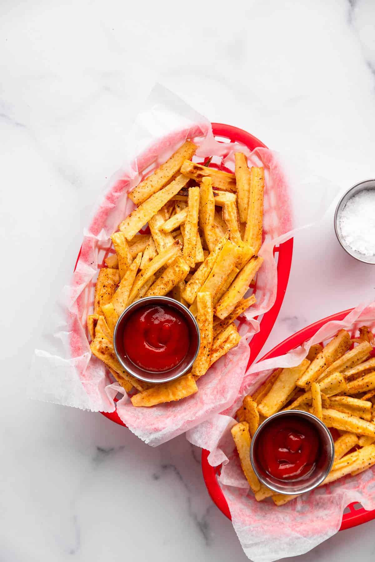 Parsnip Fries - These parsnip fries are baked, not fried, but are still crispy and delicious! A healthy alternative to French fries that is naturally gluten free and tasty! Only a few ingredients too! | #Foodfaithfitness | #Glutenfree #paleo #healthy #vegan #dairyfree Parsnip in serving basket will ketchup