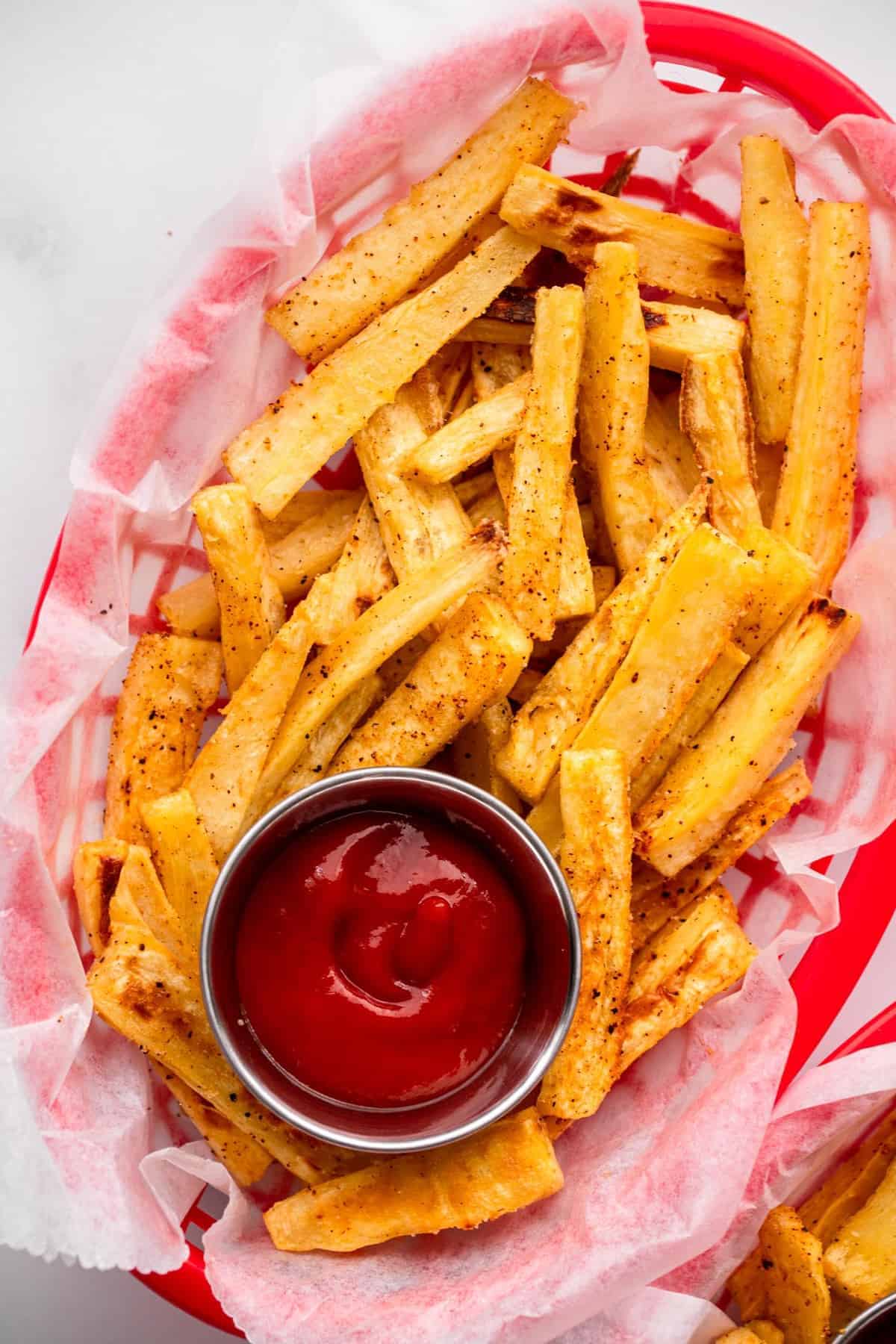 Parsnip Fries - These parsnip fries are baked, not fried, but are still crispy and delicious! A healthy alternative to French fries that is naturally gluten free and tasty! Only a few ingredients too! | #Foodfaithfitness | #Glutenfree #paleo #healthy #vegan #dairyfree Parsnip Oven Fries in a basket with ketchup close up