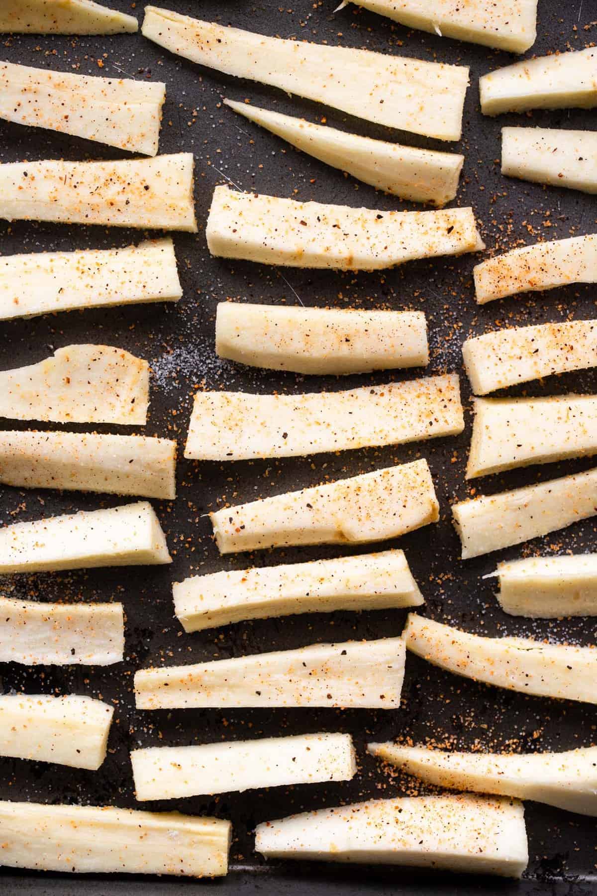 Parsnip Fries - These parsnip fries are baked, not fried, but are still crispy and delicious! A healthy alternative to French fries that is naturally gluten free and tasty! Only a few ingredients too! | #Foodfaithfitness | #Glutenfree #paleo #healthy #vegan #dairyfree Parsnips cut up on baking sheet before cooking