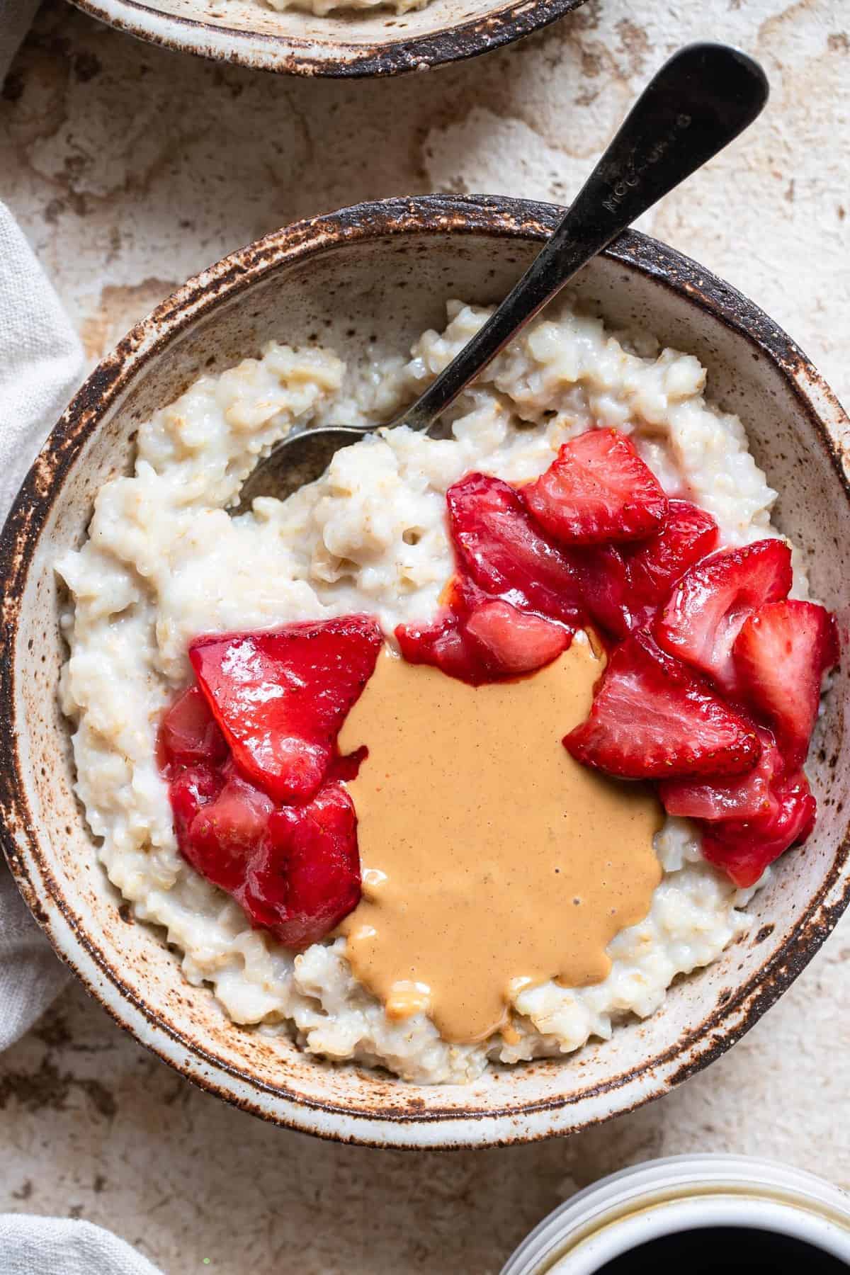 Cauliflower Protein Oats - These protein cauliflower oats are topped with sauteed strawberries for a healthy, gluten free, high protein breakfast with hidden veggies! Great for kids or adults! | #Foodfaithfitness | #glutenfree #vegetarian #healthy #breakfast close up of cauliflower protein oats with toppings in bowl