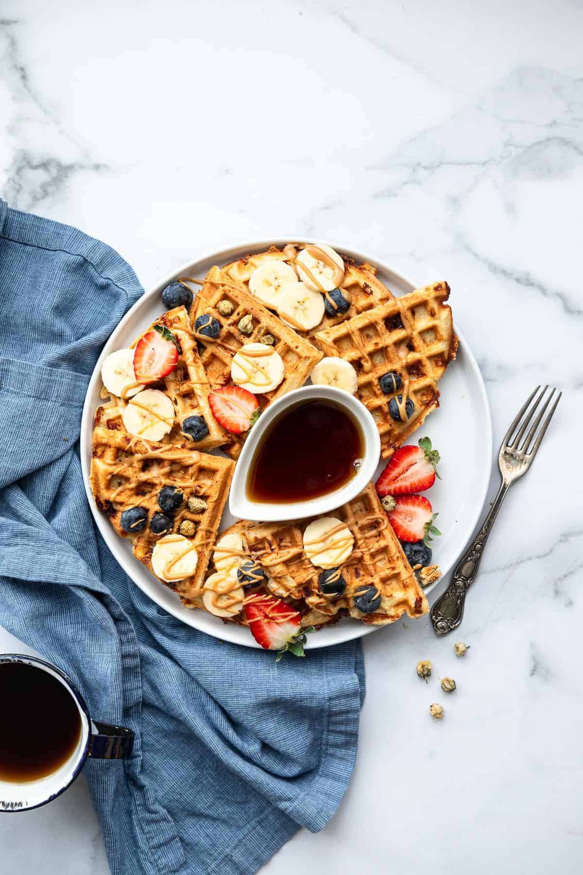 Easy Protein Waffles - These are the crispiest, fluffiest protein waffles you will ever eat! Naturally gluten free, quick, easy and so filling! A MUST MAKE. | #Foodfaithfitness | #glutenfree #healthy #waffles #breakfast protein waffles on a plate with fruit on top
