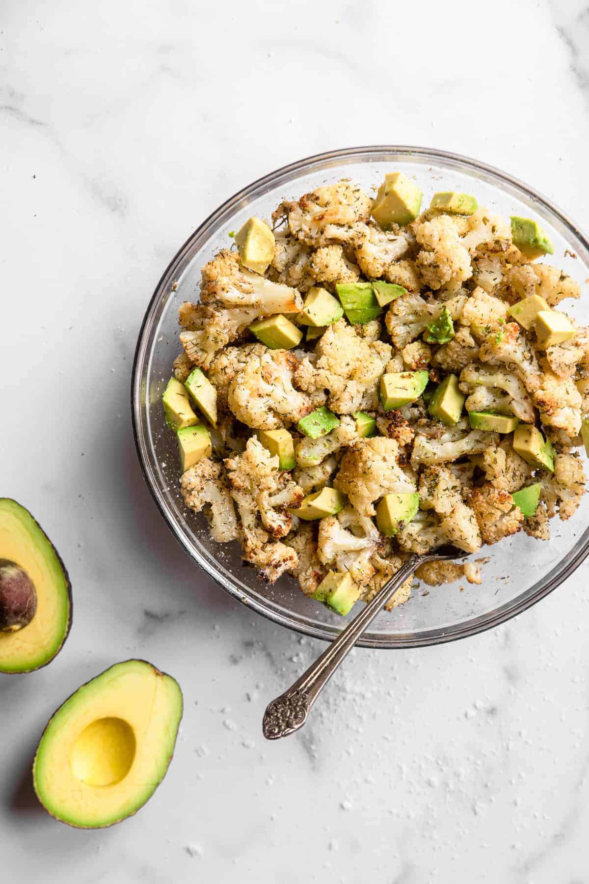 Parmesan Roasted Ranch Cauliflower - This healthy and keto friendly Parmesan Roasted Ranch Cauliflower is flavored with Parmesan, ranch seasoning and toss with avocado for a SUPER easy side dish that is kid friendly! | #Foodfaithfitness | #glutenfree #keto #lowcarb #heathy overhead view of ranch cauliflower in a bowl with avocado on the side