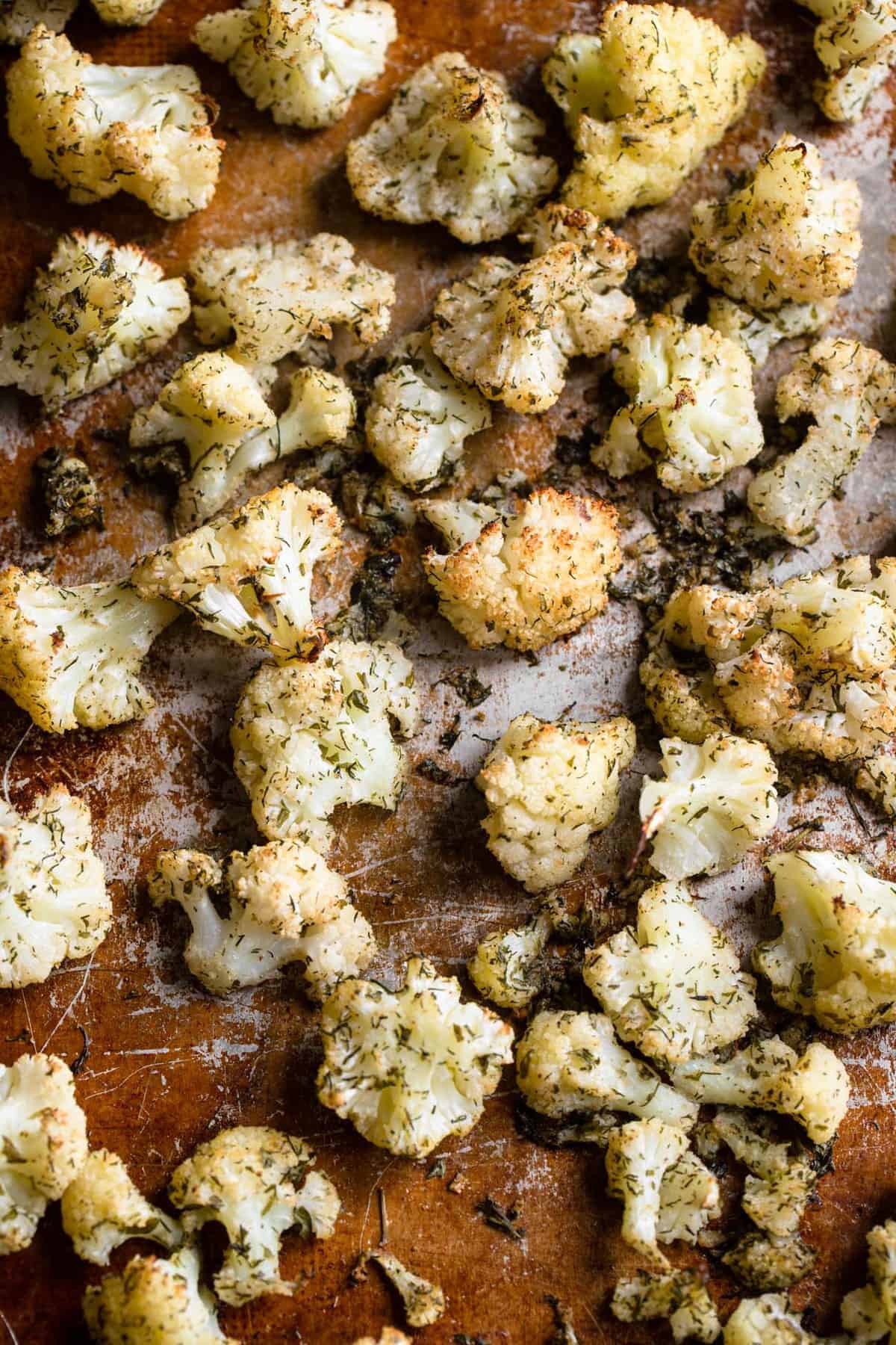 Parmesan Roasted Ranch Cauliflower - This healthy and keto friendly Parmesan Roasted Ranch Cauliflower is flavored with Parmesan, ranch seasoning and toss with avocado for a SUPER easy side dish that is kid friendly! | #Foodfaithfitness | #glutenfree #keto #lowcarb #heathy close up of ranch cauliflower being roasted on a baking sheet