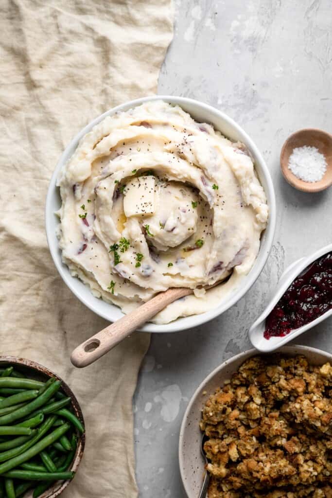 top view of red skin mashed potatoes in a bowl on a table with dressings